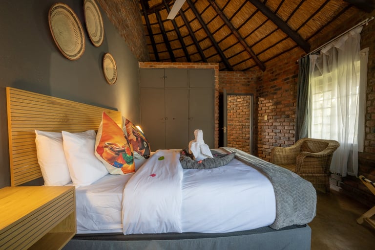 Modern bedroom with wooden slat headboard, white bedding, exposed brick walls, woven ceiling, and decorative plates on wall