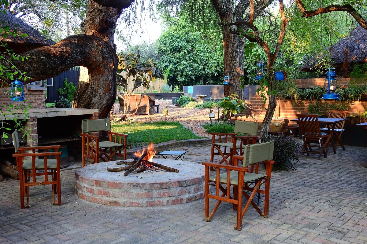 Outdoor seating area with wooden chairs around a brick fire pit