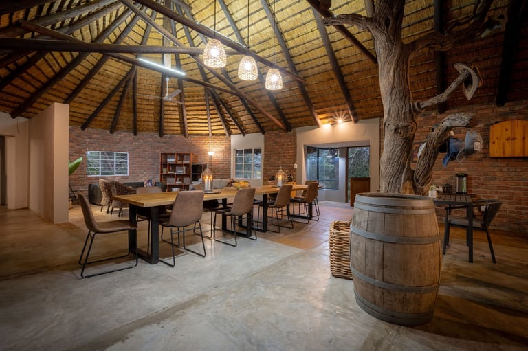 Modern loft interior with dining area, exposed wooden beams, brick walls, and a wooden barrel accent