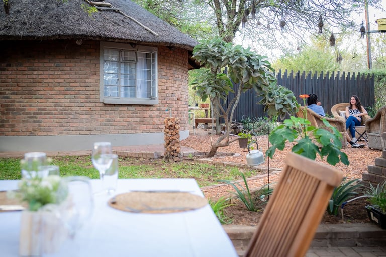 Backyard gathering at brick cottage with set table in foreground, garden, and people enjoying outdoor space by fence